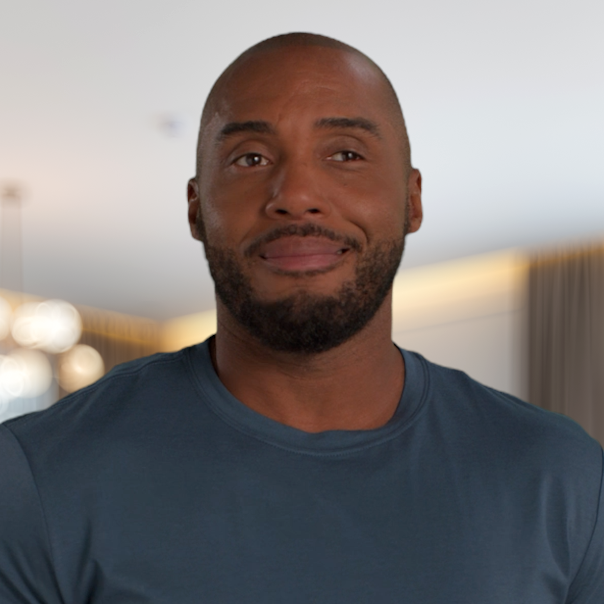Woman with curly hair wearing a red top and white cardigan indoors